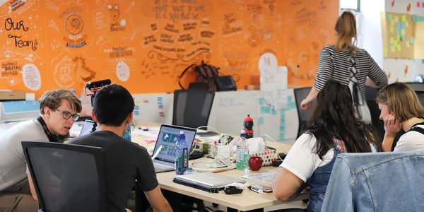 Three people sitting at a desk in the co-working space