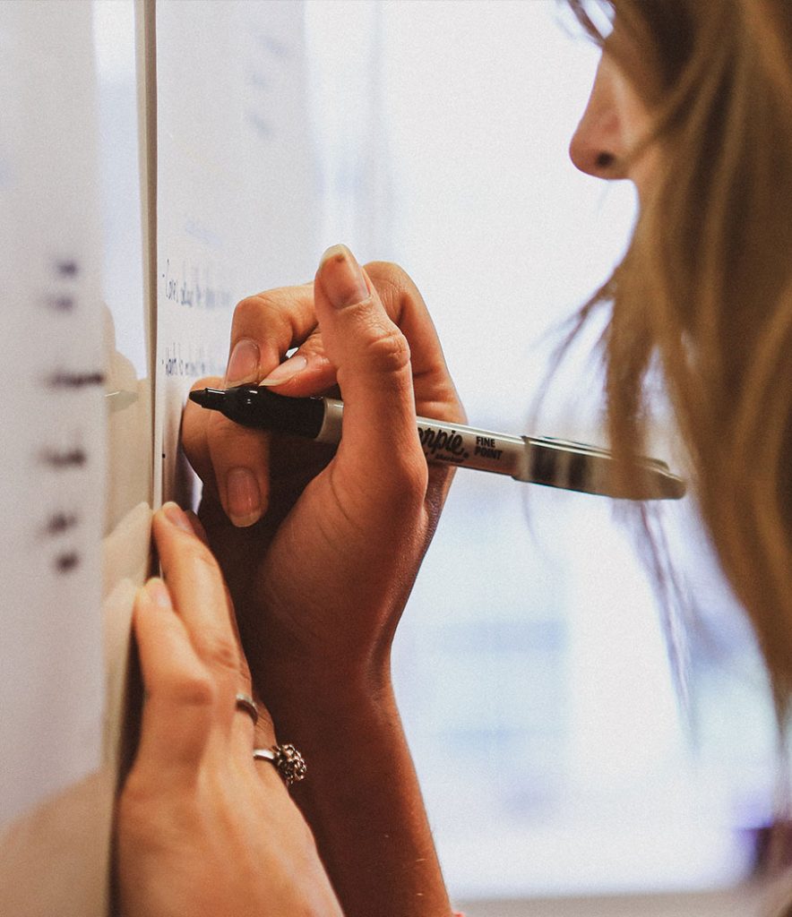 Woman writing on whiteboard in a Creative HQ workshop